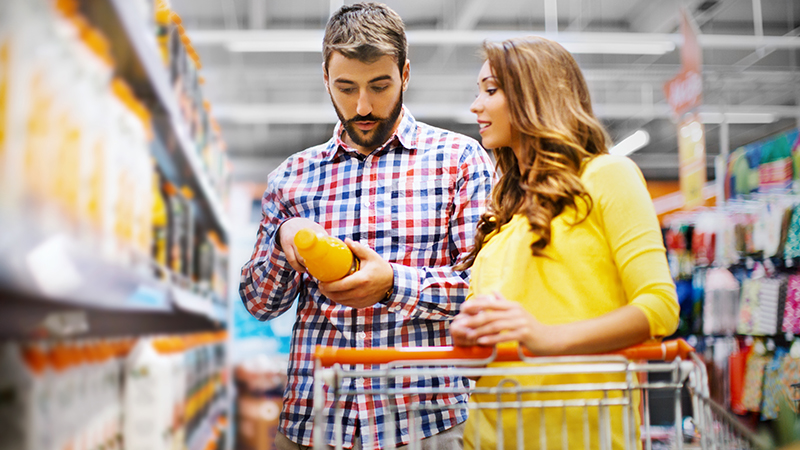Casal num supermercado a ler o rótulo de uma garrafa